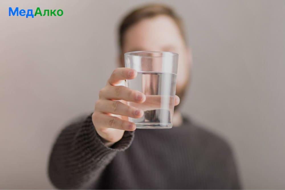 Человек держит в руке стакан воды
